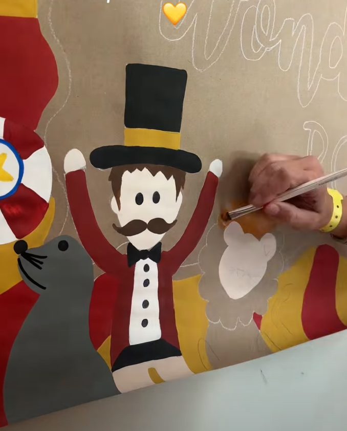 Leeann painting a circus banner by hand